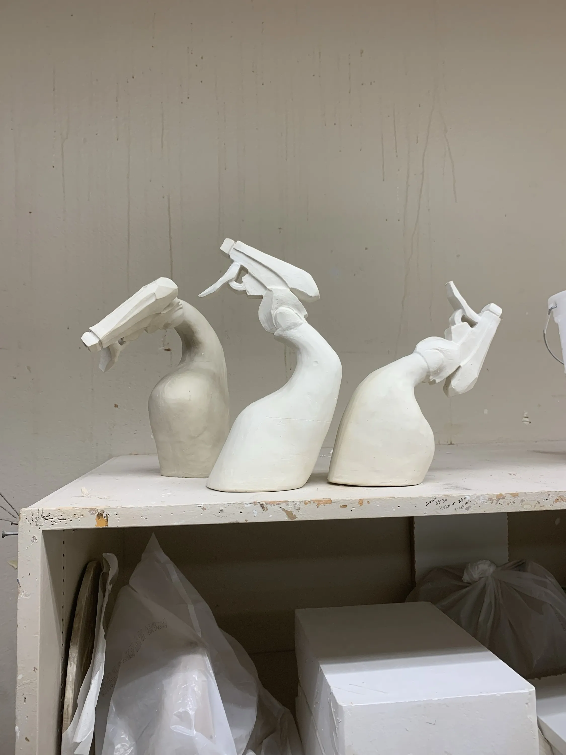 Three spray bottle sculptures in bisque on the shelf, pre-glaze